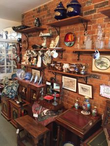 Shelves of antiques against an exposed brick wall in the shop