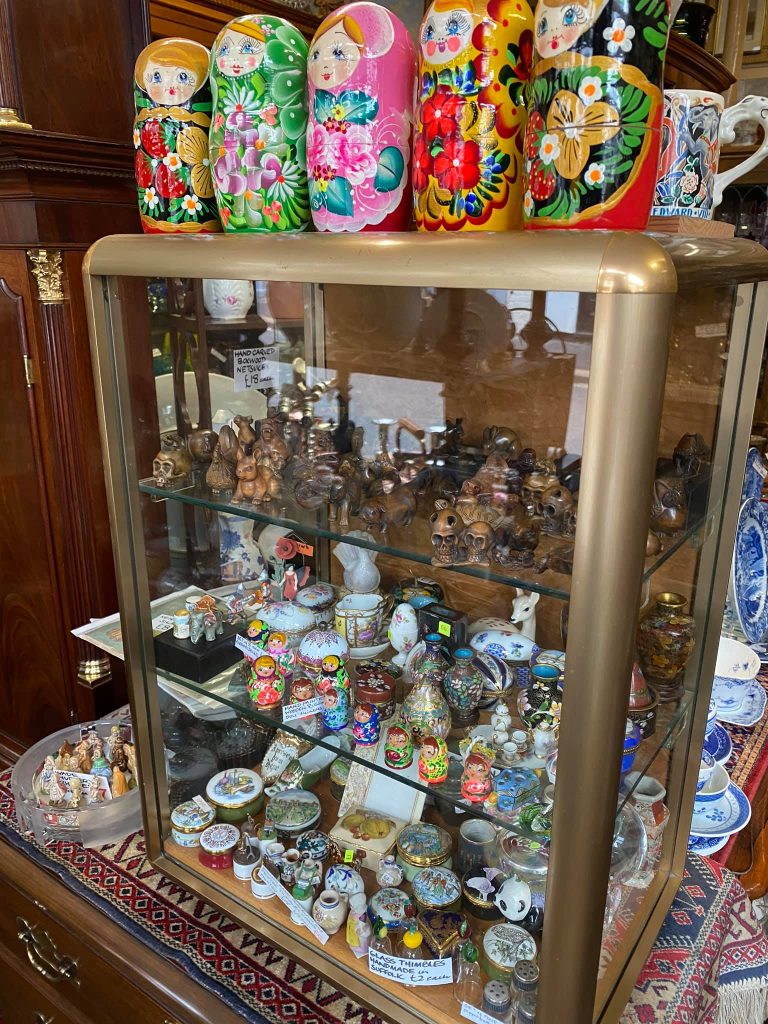 A cabinet of small collectable treasures including nesting dolls and trinket boxes